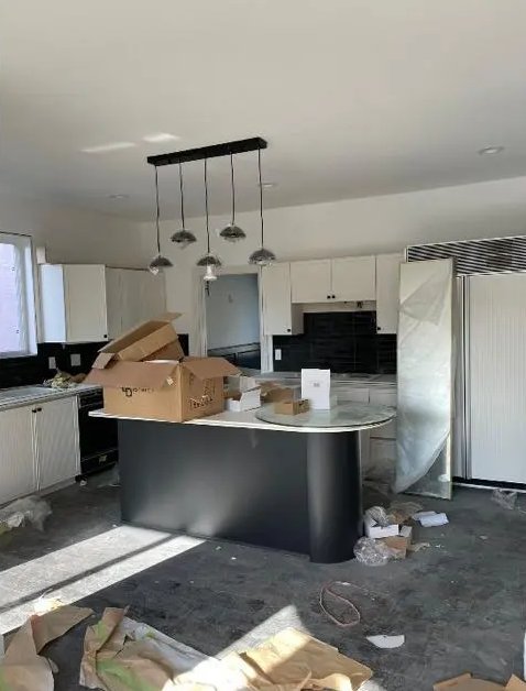 Kitchen cluttered with moving boxes and debris before a move-in cleaning