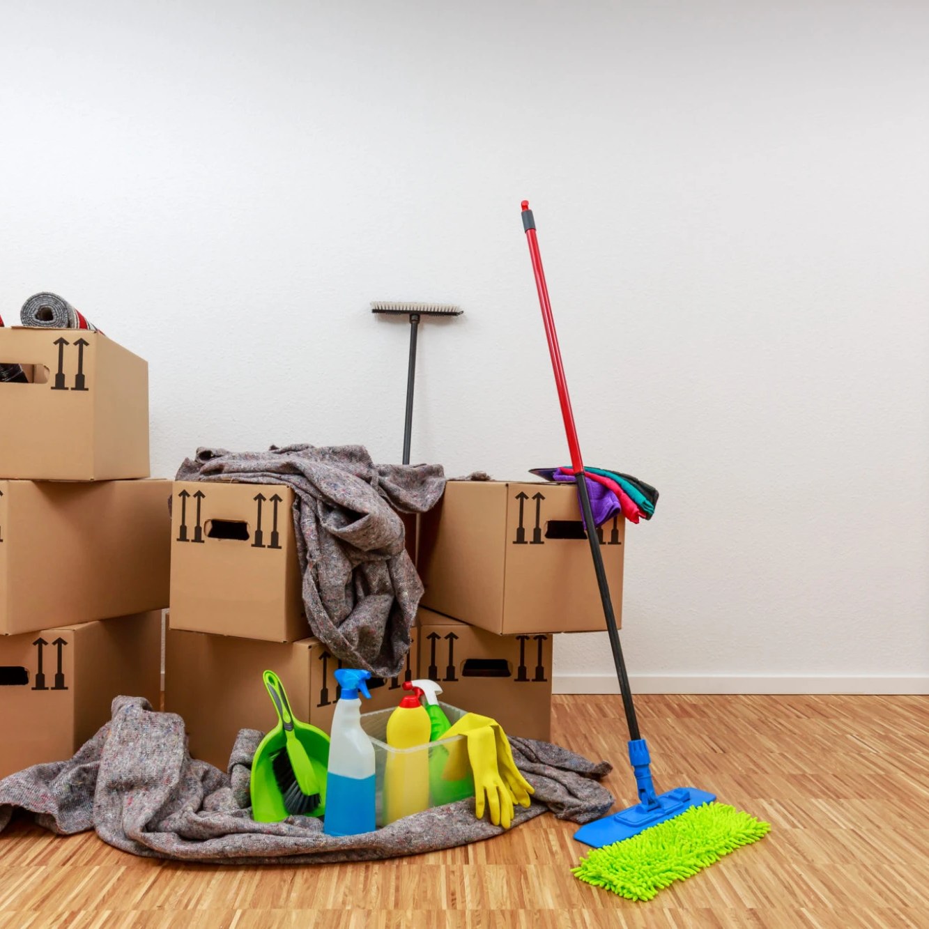Moving boxes and cleaning supplies staged in an empty room, ready for a move-in cleaning