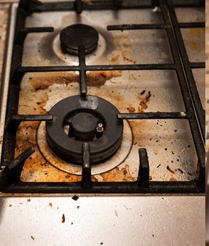 Greasy, grime-covered stovetop before an Amelia Shine Cleaning Services visit